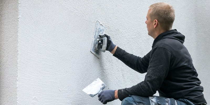Maçon appliquant enduit à la chaux sur la façade