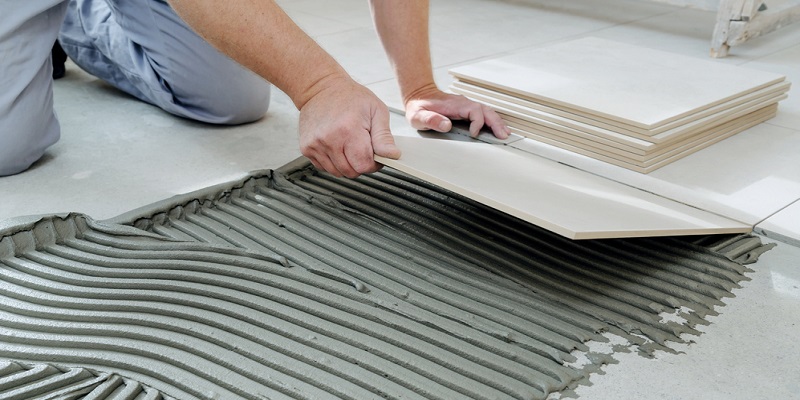 Carreleur en train de poser un carrelage intérieur