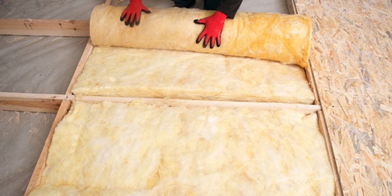 Pose de laine de verre entre les solives d'un plancher