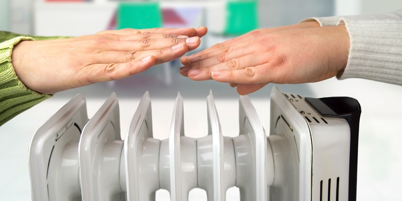 Des mains se réchauffent au dessus d'un radiateur bain d'huile