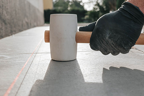 Photo d'ambiance homme qui pose des dalles au marteau