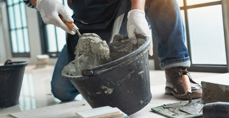 Ouvrier préparant du mortier dans un seau de maçon